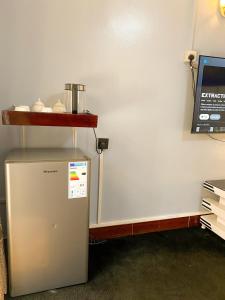 a small refrigerator in a room with a shelf on the wall at Royal Lake View Gardens in Kampala