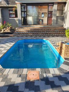 a blue swimming pool in front of a house at Ludiz Self Catering Guest House in Avondale