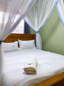 a white bed with a blanket on top of it at Royal Lake View Gardens in Kampala