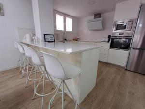 a kitchen with a bar with white counter tops and stools at Carbo Home y Garaje , Algemesí Home in Algemesí