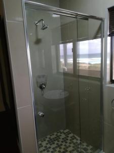 a bathroom with a glass shower with a sink at Palmnut Lodge in Durban