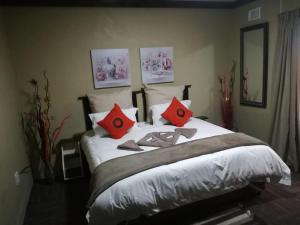 a bedroom with a large bed with red pillows at Palmnut Lodge in Durban