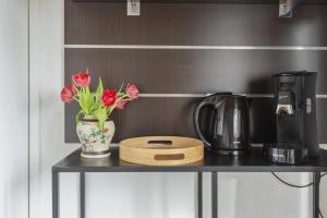 a table with a vase of flowers and a coffee maker at Appartement Zuid 5 strand op 2 minuten lopen in Zandvoort