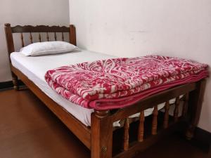 a bed with a red and white blanket on it at Coorg rest house in Madikeri