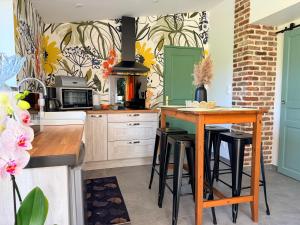 a kitchen with a table with stools and a stove at Au bord de l'étang in Saint-Aubin