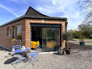 a small brick building with chairs and a table at Au bord de l'étang in Saint-Aubin