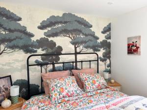 a bedroom with a bed and a painting of trees at Au bord de l'étang in Saint-Aubin