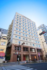 a tall white building on a city street with a traffic light at Hotel Keihan Asakusa in Tokyo