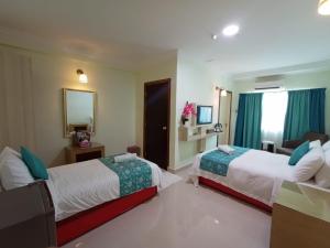 a hotel room with two beds and a mirror at Che Wok Hotel in Kota Bharu