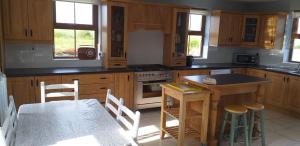 a kitchen with wooden cabinets and a table and chairs at Sleeps6-FamilyFriendly-FreeParking-Garden in Ballybunion