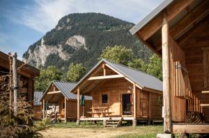 a group of wooden cabins with a mountain in the background at Huttopia Bourg St Maurice in Bourg-Saint-Maurice +17 photos