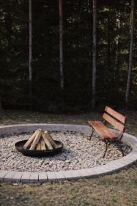 a fire pit with a bench next to a park at Dom przy Lesie z sauną in Augustów