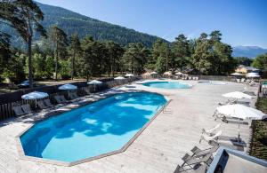 a resort with two pools and umbrellas and chairs at Huttopia Bourg St Maurice in Bourg-Saint-Maurice