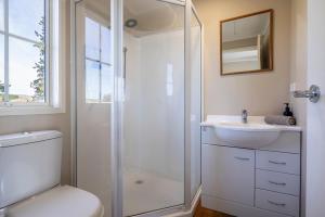 a bathroom with a shower and a toilet and a sink at Wedderburn Cottages in Wedderburn +11 photos