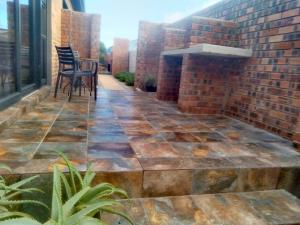 a patio with chairs and a brick wall at Lavender Suite in Gansbaai
