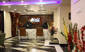 a lobby with two people sitting at a table with a tv at The Hoften Al Shaykh Resorts, Srinagar in Srinagar