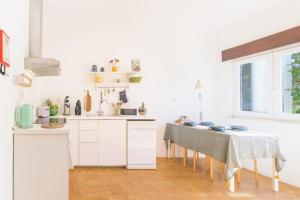 a kitchen with white cabinets and a table with chairs at Casa Bettina in Vila Nova de Milfontes
