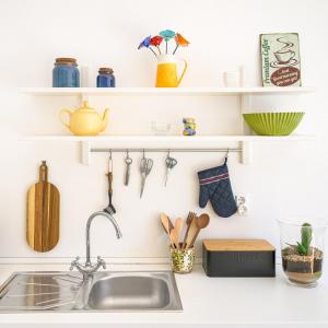 a kitchen counter with a sink and shelves with utensils at Casa Bettina in Vila Nova de Milfontes