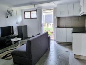 a living room with a couch and a kitchen at Golf Road Guesthouse in Pietermaritzburg