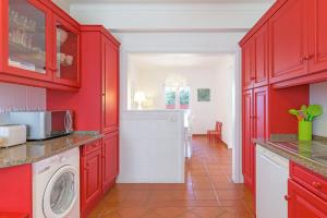 a kitchen with red cabinets and a washer and dryer at Casa Buganvília in Sines +22 photos