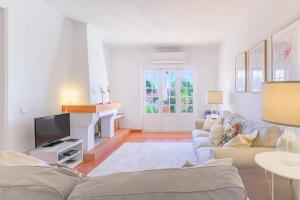 a living room with a couch and a tv at Casa Buganvília in Sines