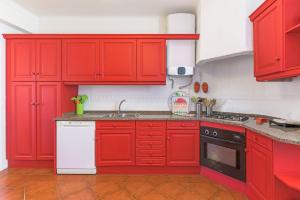 a red kitchen with white appliances and red cabinets at Casa Buganvília in Sines