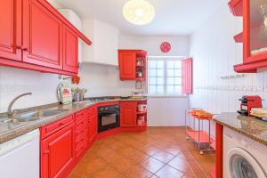 a kitchen with red cabinets and a sink at Casa Buganvília in Sines