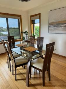 a dining room with a glass table and chairs at Tarkine Retreat in Penguin