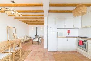 a kitchen and living room with white cabinets and a table at Casa Sol Limão in Zambujeira do Mar +15 photos