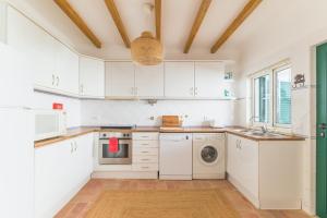a kitchen with white cabinets and a washer and dryer at Casa Sol Limão in Zambujeira do Mar