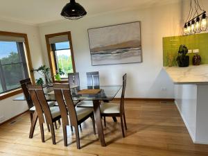 a dining room with a glass table and chairs at Tarkine Retreat in Penguin +16 photos