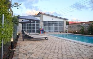 a pool with benches and an umbrella next to a house at Mawi Homes in Lusaka