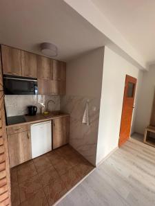 a kitchen with wooden cabinets and a microwave at SUN & WINE in Pobierowo