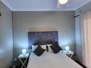 a bedroom with a large white bed with two tables at Golf Road Guesthouse in Pietermaritzburg