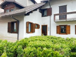 a white house with wooden windows and bushes at Casa Primavera in Agordo