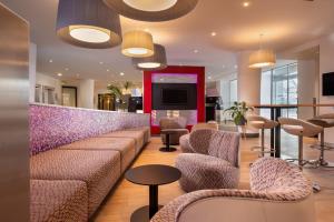 a lobby with couches and chairs and a tv at IntercityHotel Frankfurt Airport Terminal 3 in Frankfurt