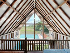 an attic room with a large window and a swimming pool at Nglaras Resort Yogyakarta in Ngaglik