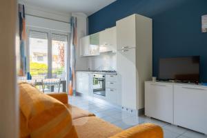 a kitchen with white cabinets and a tv and a couch at Homiday - Appartamenti I Gabbiani in Pineto