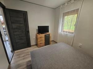 a bedroom with a bed and a tv and a door at Dream vendégház in Vásárosnamény
