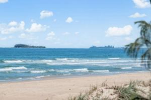 a beach with a view of the ocean and an island at Pawfect Coastal - Pet friendly Beachfront Pool in Marcoola