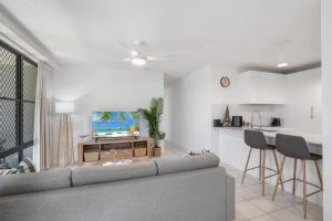 a white living room with a couch and a kitchen at Pawfect Coastal - Pet friendly Beachfront Pool in Marcoola