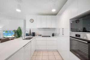a white kitchen with a sink and a stove at Pawfect Coastal - Pet friendly Beachfront Pool in Marcoola +22 photos