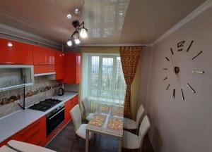 a kitchen with red cabinets and a clock on the wall at СУЧАСНА НОВА КВАРТИРА in Lutsk