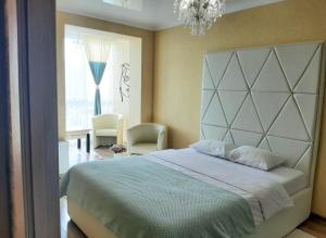 a bedroom with a large bed and a chandelier at СУЧАСНА НОВА КВАРТИРА in Lutsk