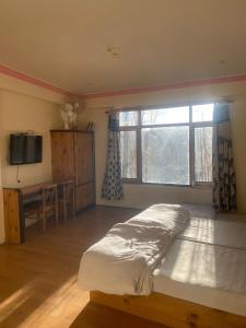 a bedroom with a bed and a desk and a window at Summer Villa in Leh
