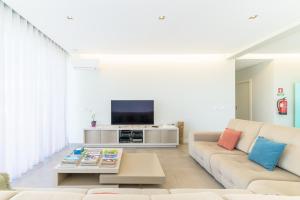 a living room with a couch and a tv at Vila Praia Grande in Sines