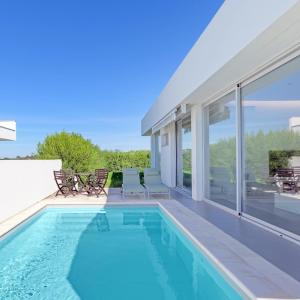a swimming pool with chairs and a house at Vila Praia Grande in Sines +31 photos