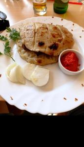 ein weißer Teller mit einem Sandwich und einer Schüssel Soße in der Unterkunft Hotel Split in Glamoč + 2 Fotos