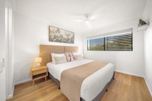 a white bedroom with a bed and a window at Coastal Drift - Beach Access Pool Spa Gym in Marcoola