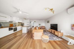 a kitchen and living room with a couch and a table at Coastal Drift - Beach Access Pool Spa Gym in Marcoola